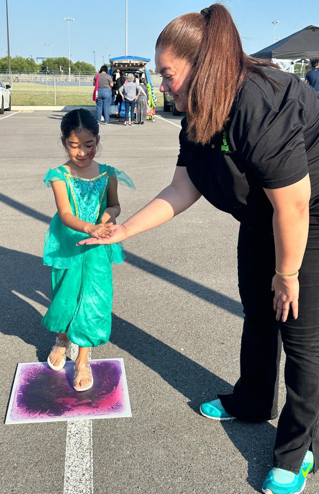A woman is standing next to a little girl in a green dress.