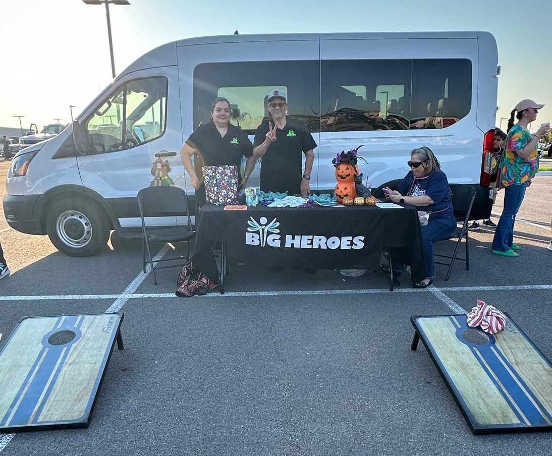 A group of people standing around a table in front of a van.