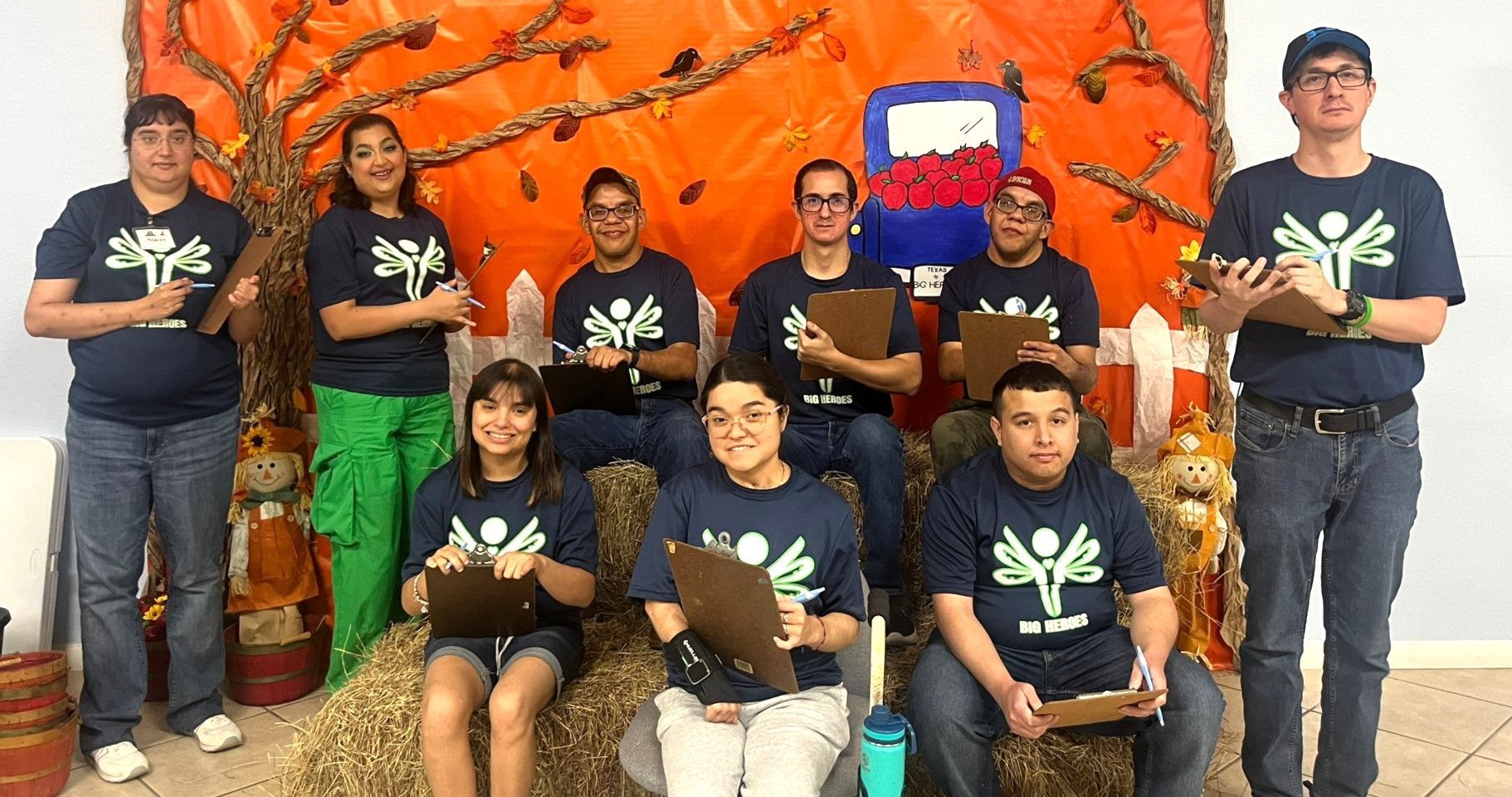 A group of people are posing for a picture in front of an orange wall.