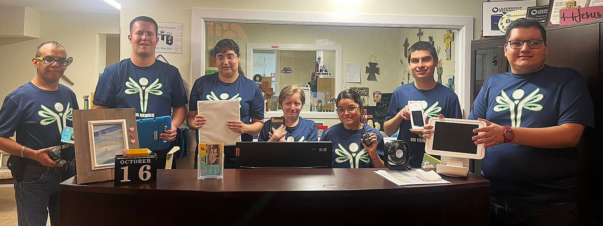 A group of people in blue shirts are standing around a table.