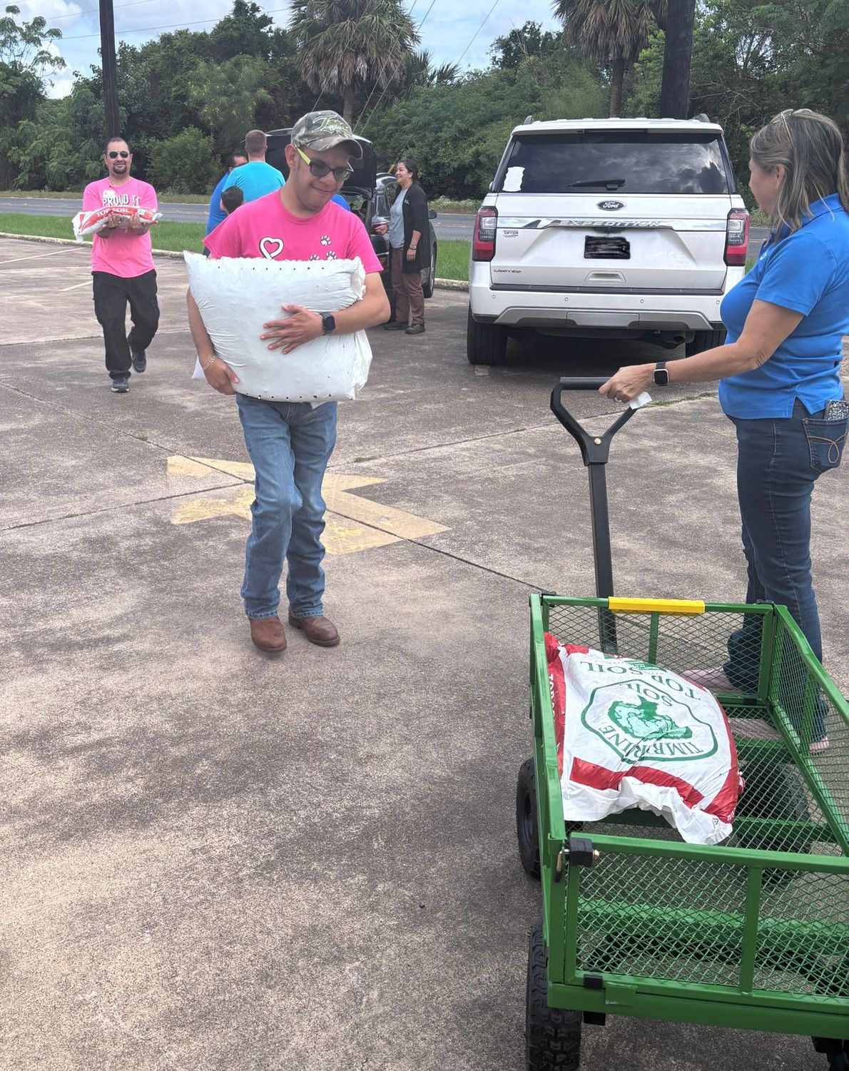 A man is carrying a large white pillow on a green cart.