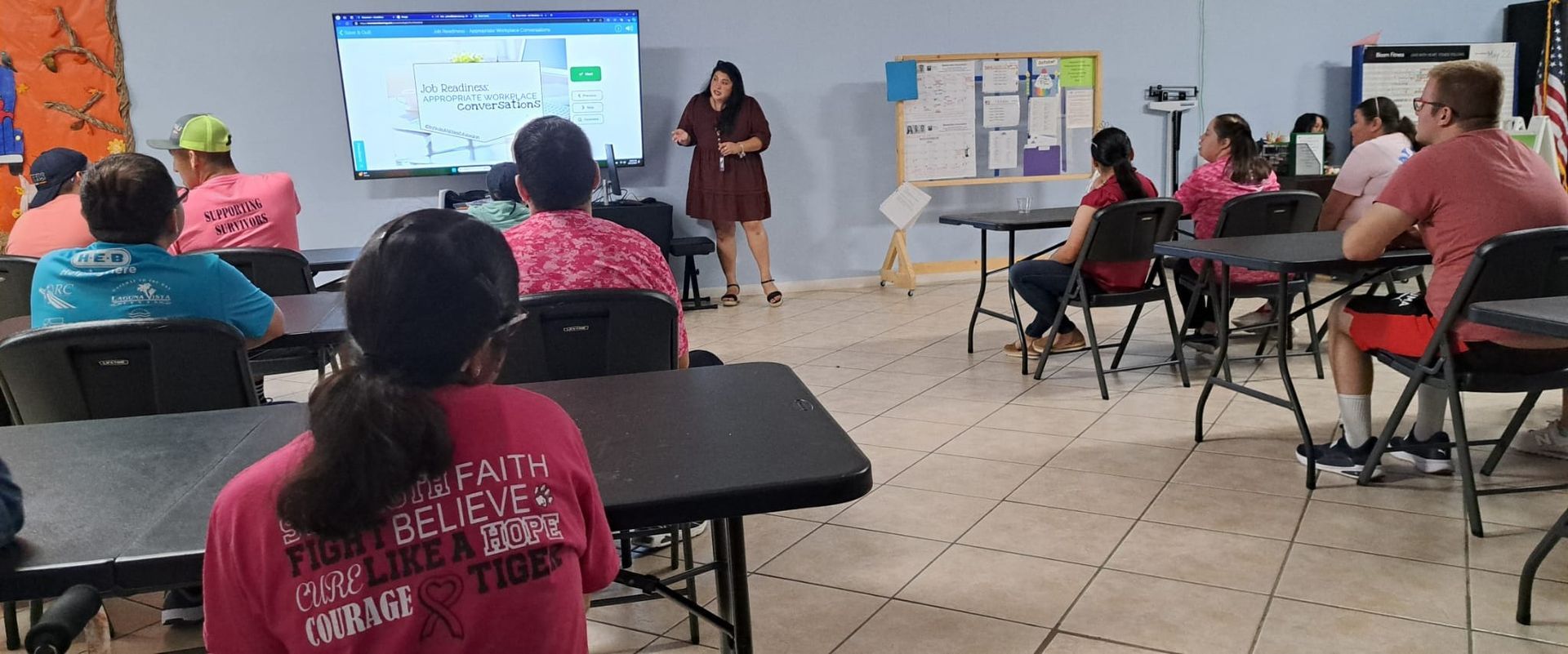 A woman is giving a presentation to a group of people in a classroom.