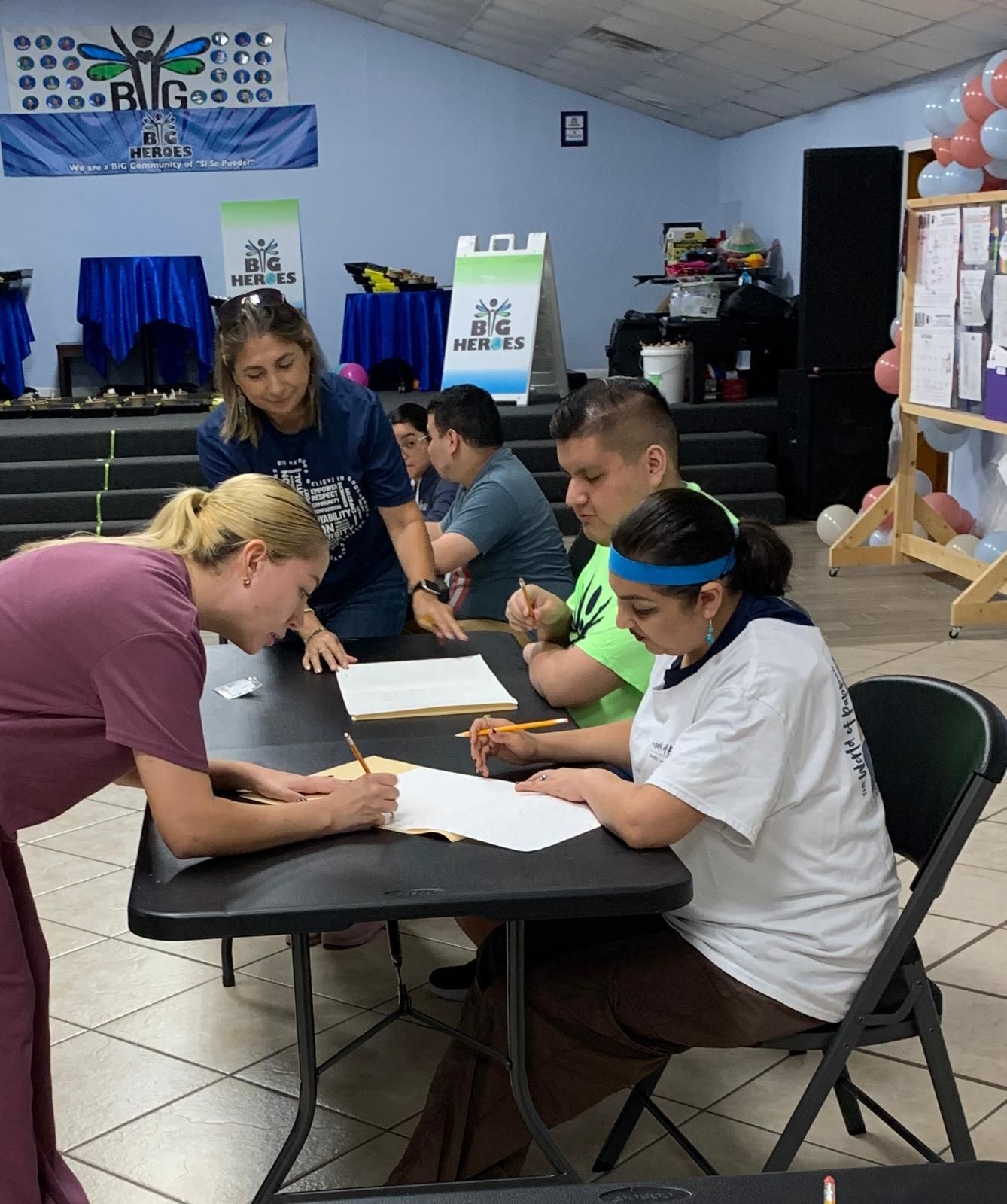 A group of people are sitting at a table in front of a sign that says big