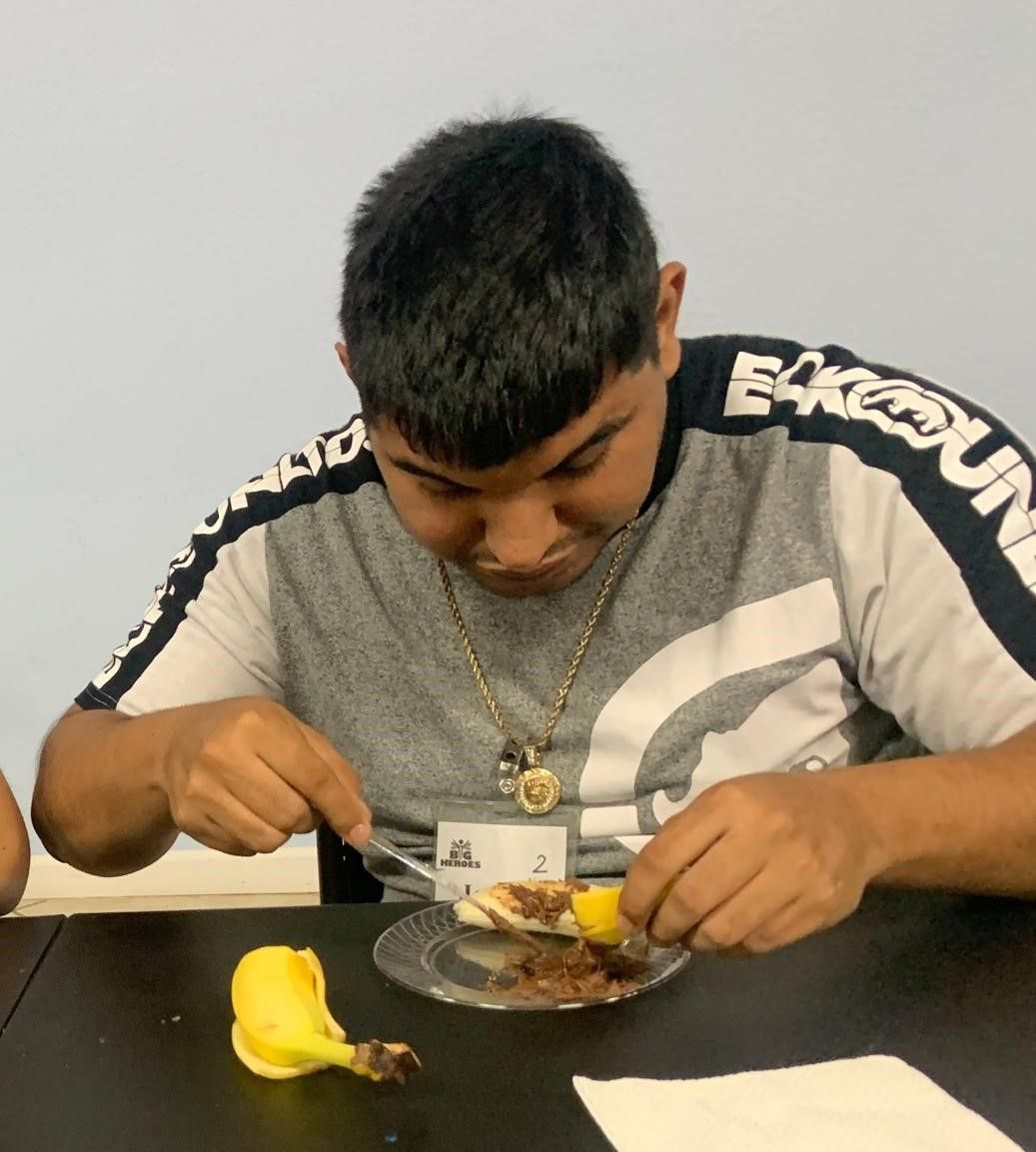 A man wearing a shirt that says ecko unltd is eating a plate of food