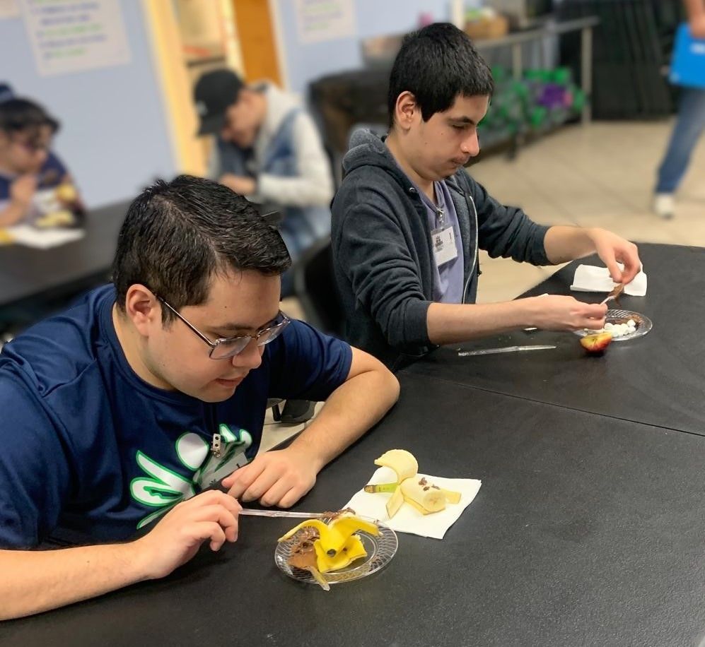 Two young men are sitting at a table eating food