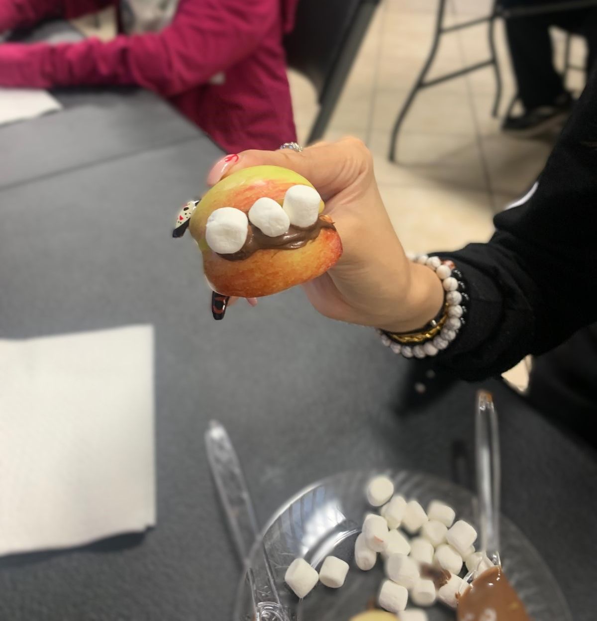 A person is holding an apple with marshmallows on it