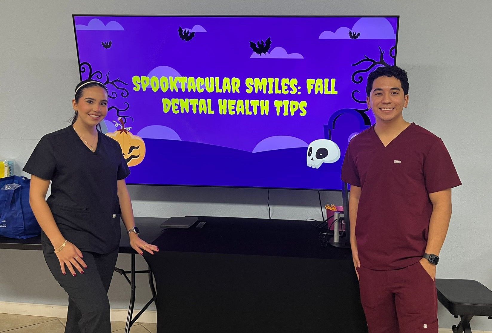 A man and a woman are standing in front of a screen that says spooktacular smiles fall dental health tips