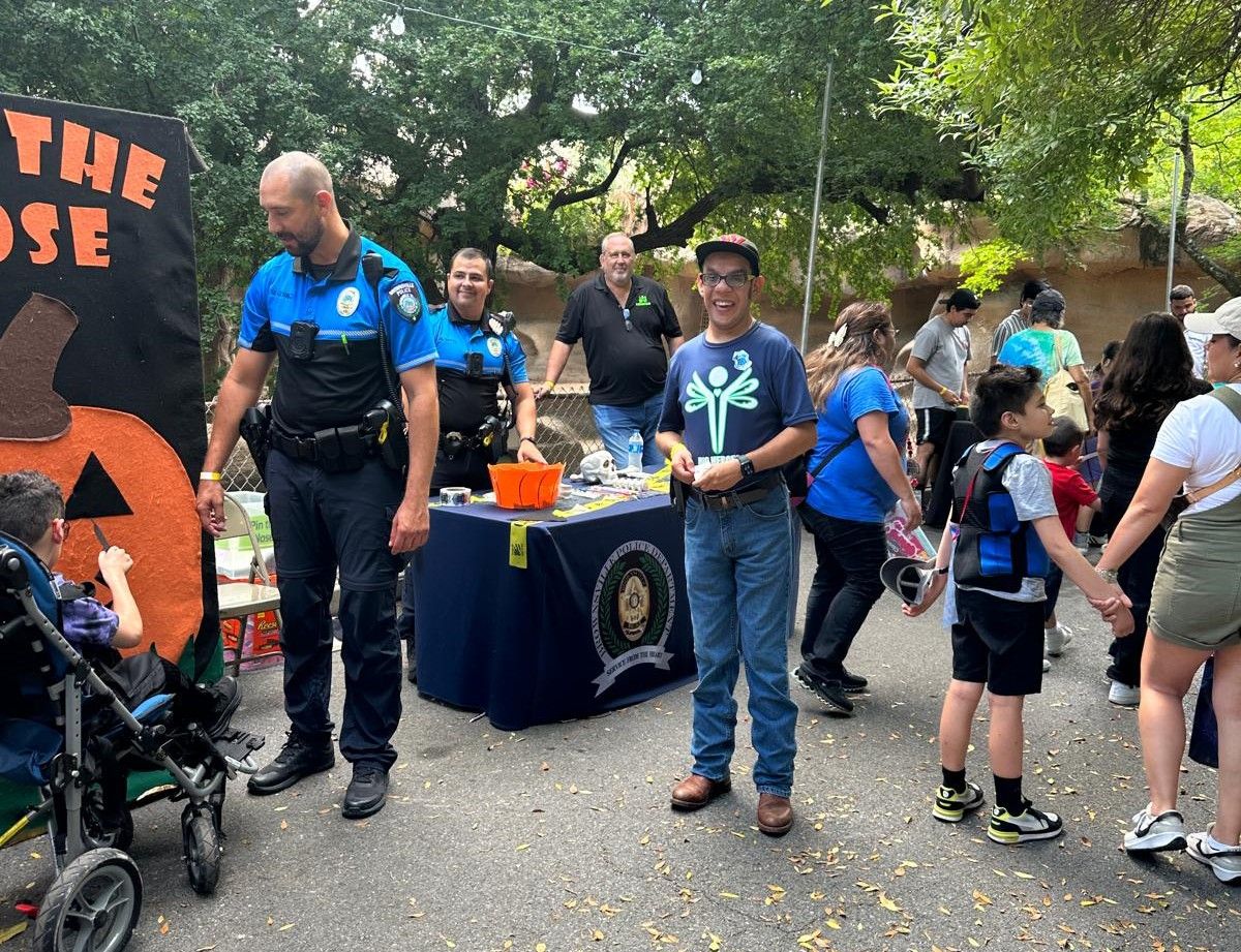 A group of people are standing around a table at a halloween event.