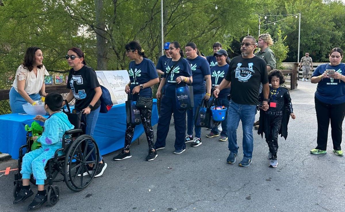 A group of people are walking down a street with a child in a wheelchair.
