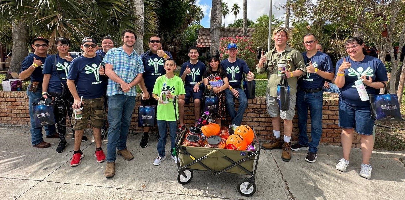 A group of people standing next to a wagon filled with pumpkins.