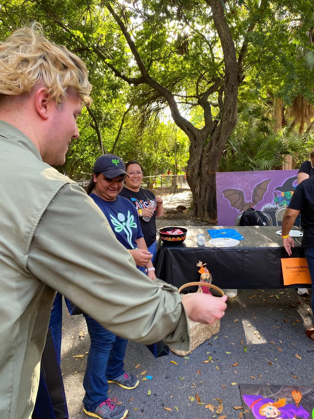 A group of people are standing around a table in a park.