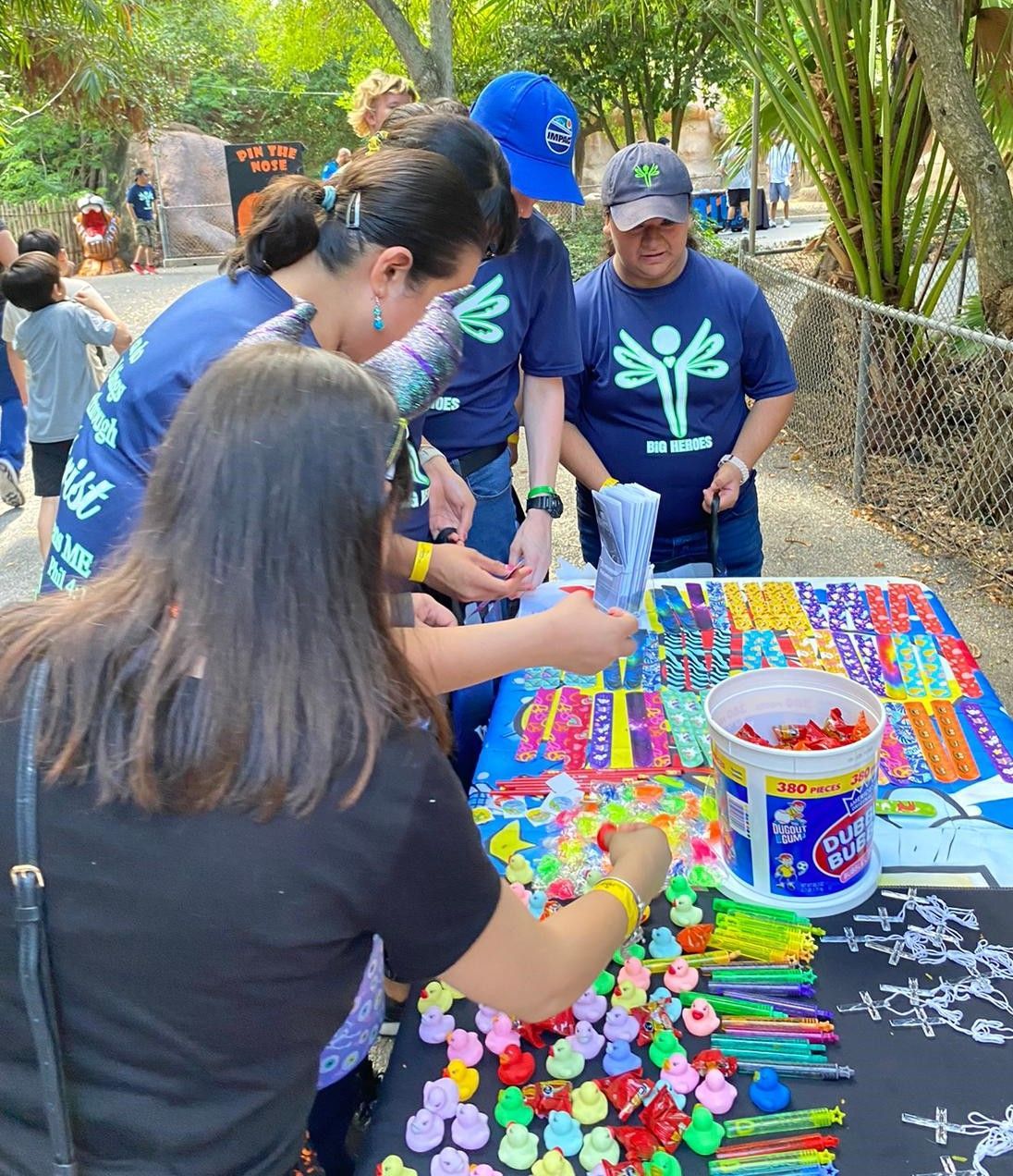 A group of people are gathered around a table filled with colorful toys.
