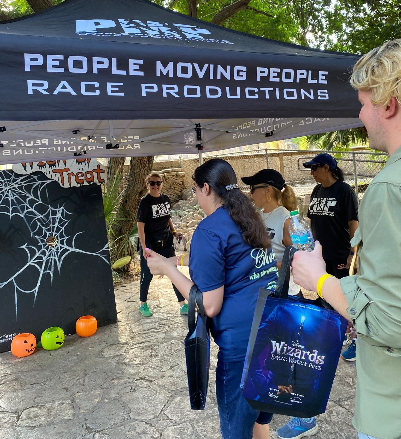 A group of people standing under a tent that says people moving people rage productions