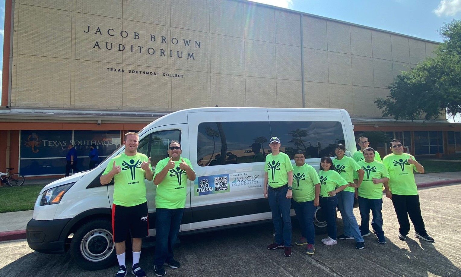 A group of people are standing in front of a van.