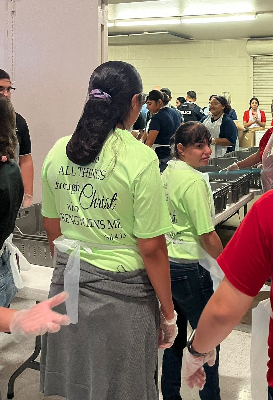 A woman wearing a green shirt that says all things through christ