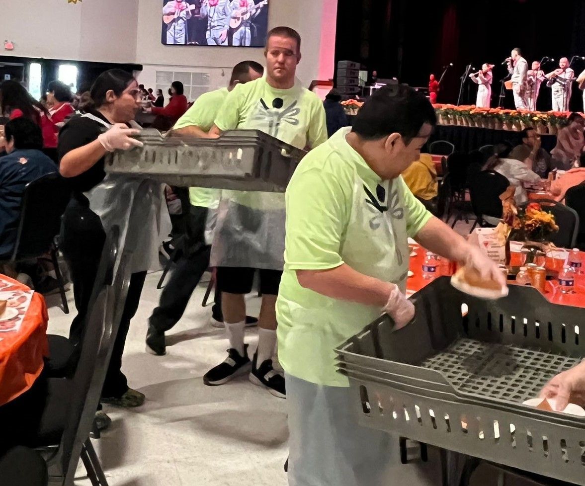 A man in a green shirt is serving food to a crowd of people