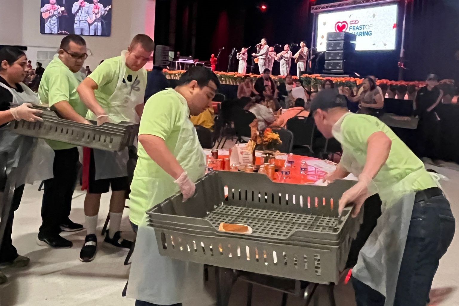 A group of people are standing around a table holding trays of food.