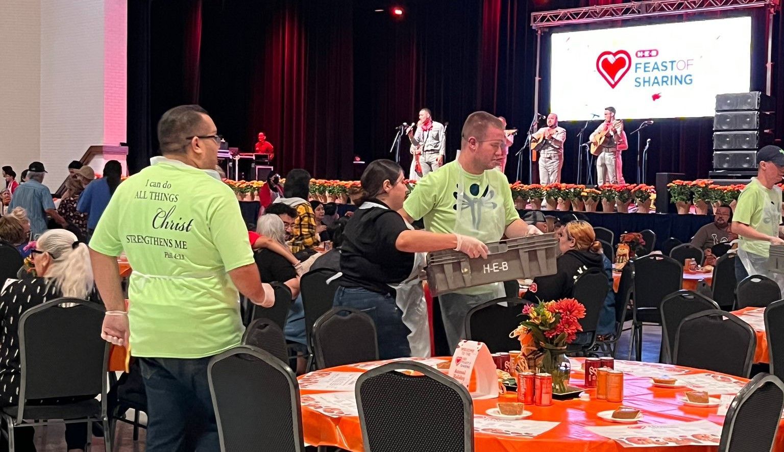 A group of people are standing in a room with tables and chairs.