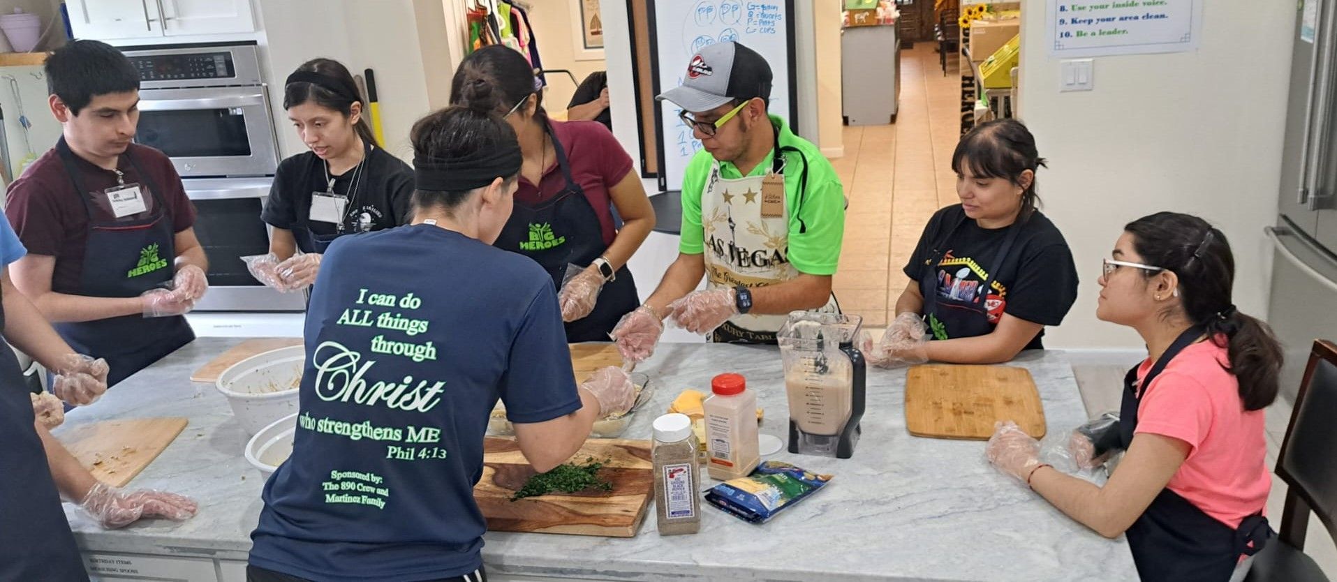 A group of people are sitting around a table in a kitchen preparing food.