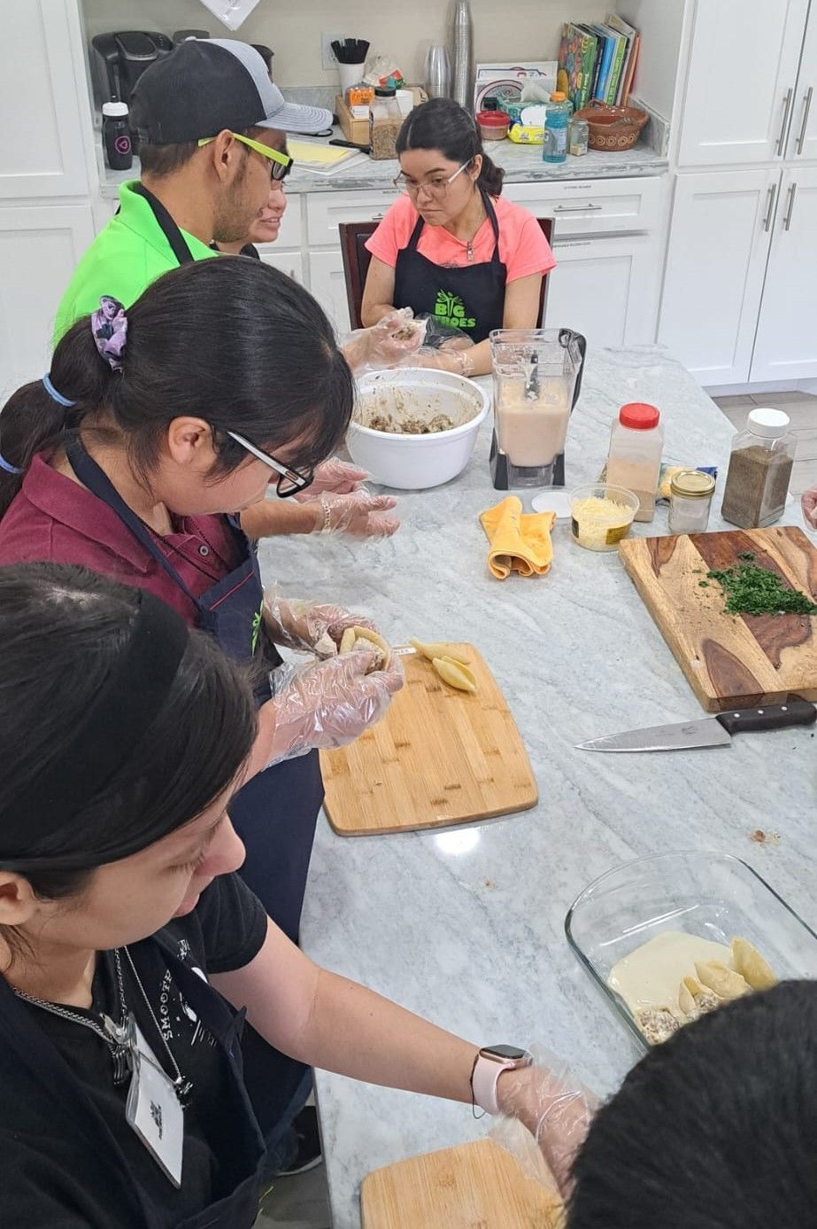 A group of people are sitting around a table in a kitchen preparing food.