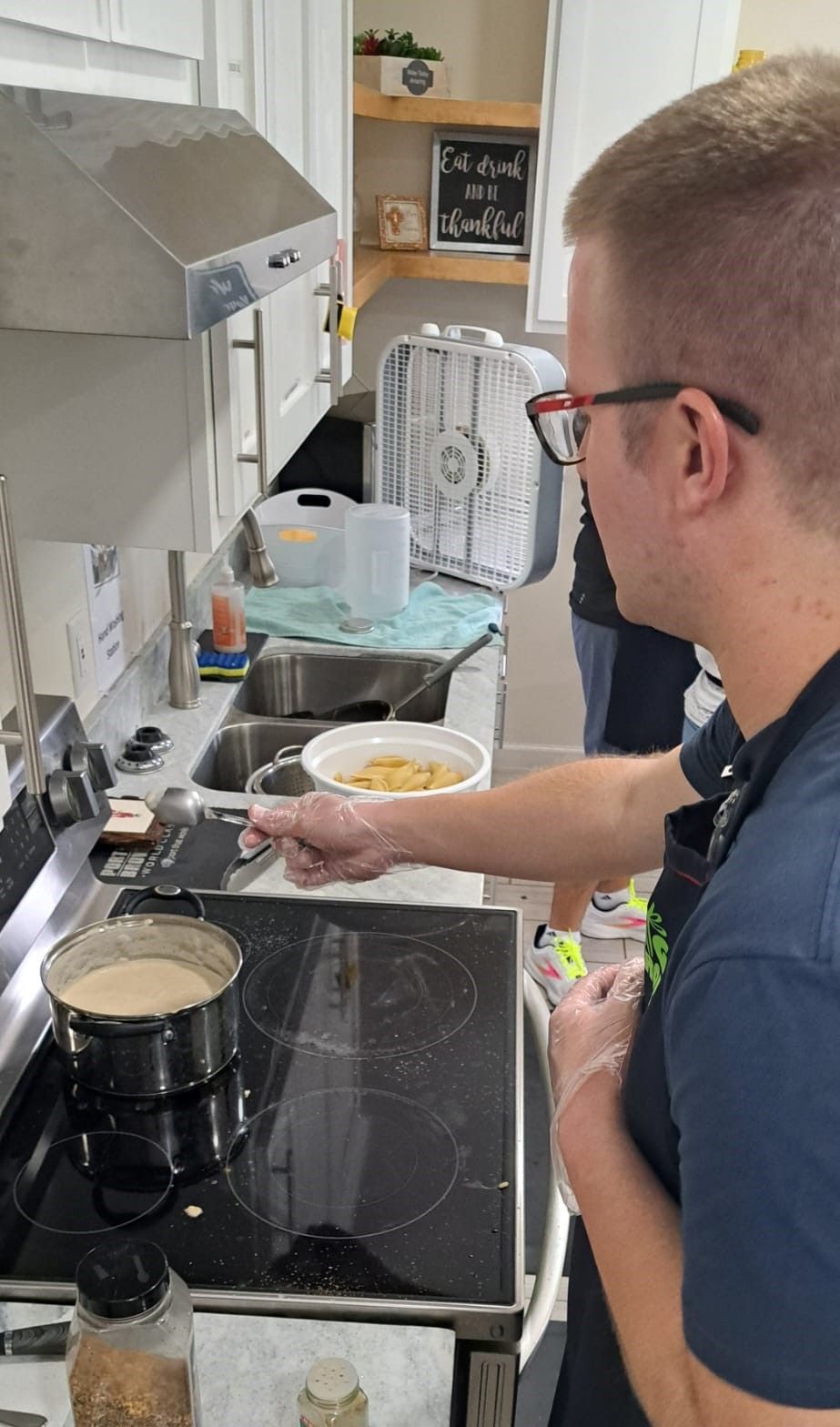 A man is cooking food on a stove in a kitchen.