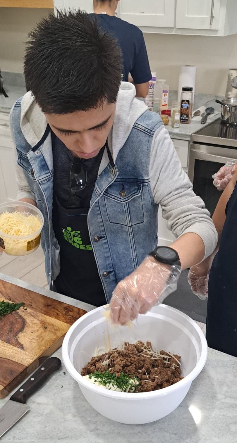 A young man is preparing food in a bowl in a kitchen.