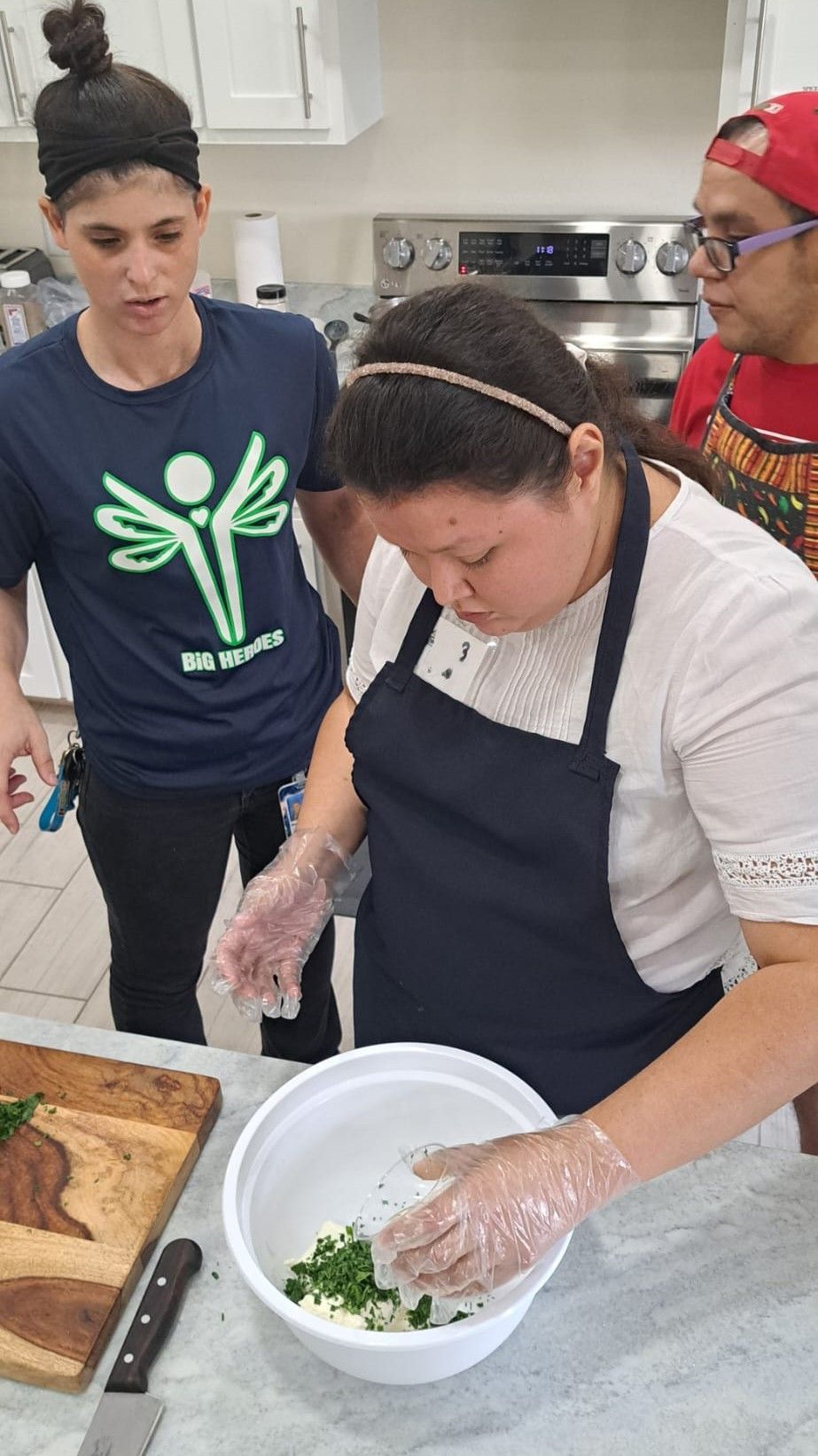 A group of people are standing around a table in a kitchen preparing food.