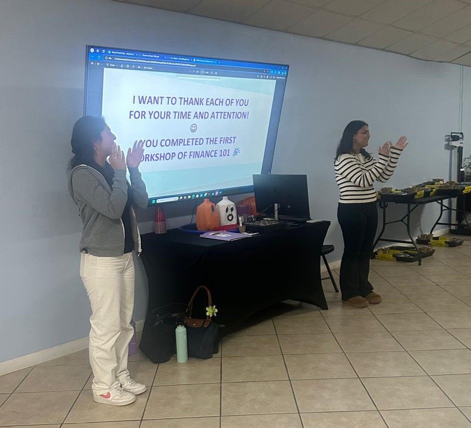 Two women standing in front of a projector screen that says