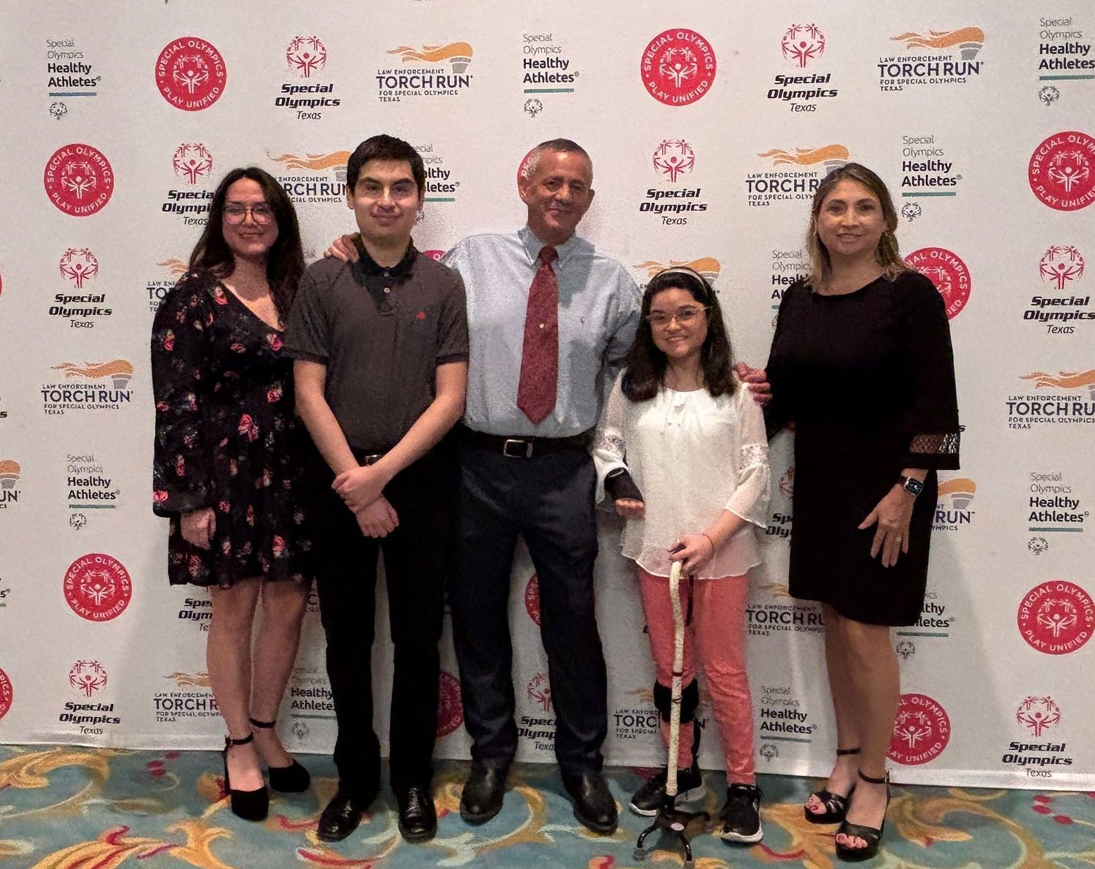 A group of people are posing for a picture in front of a wall with logos on it