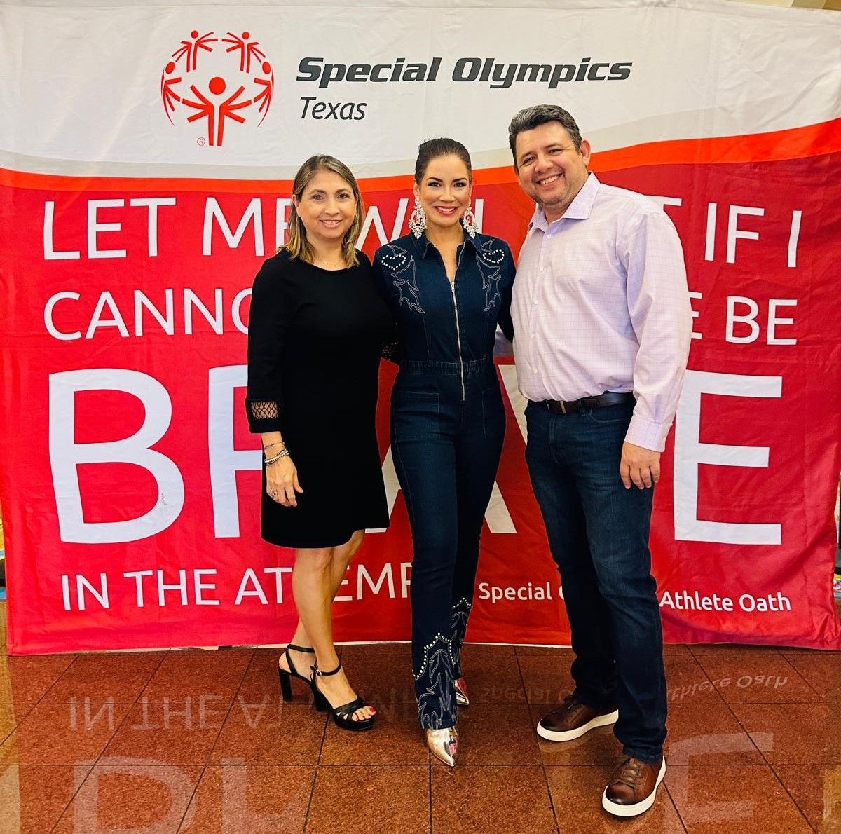Three people standing in front of a special olympics banner
