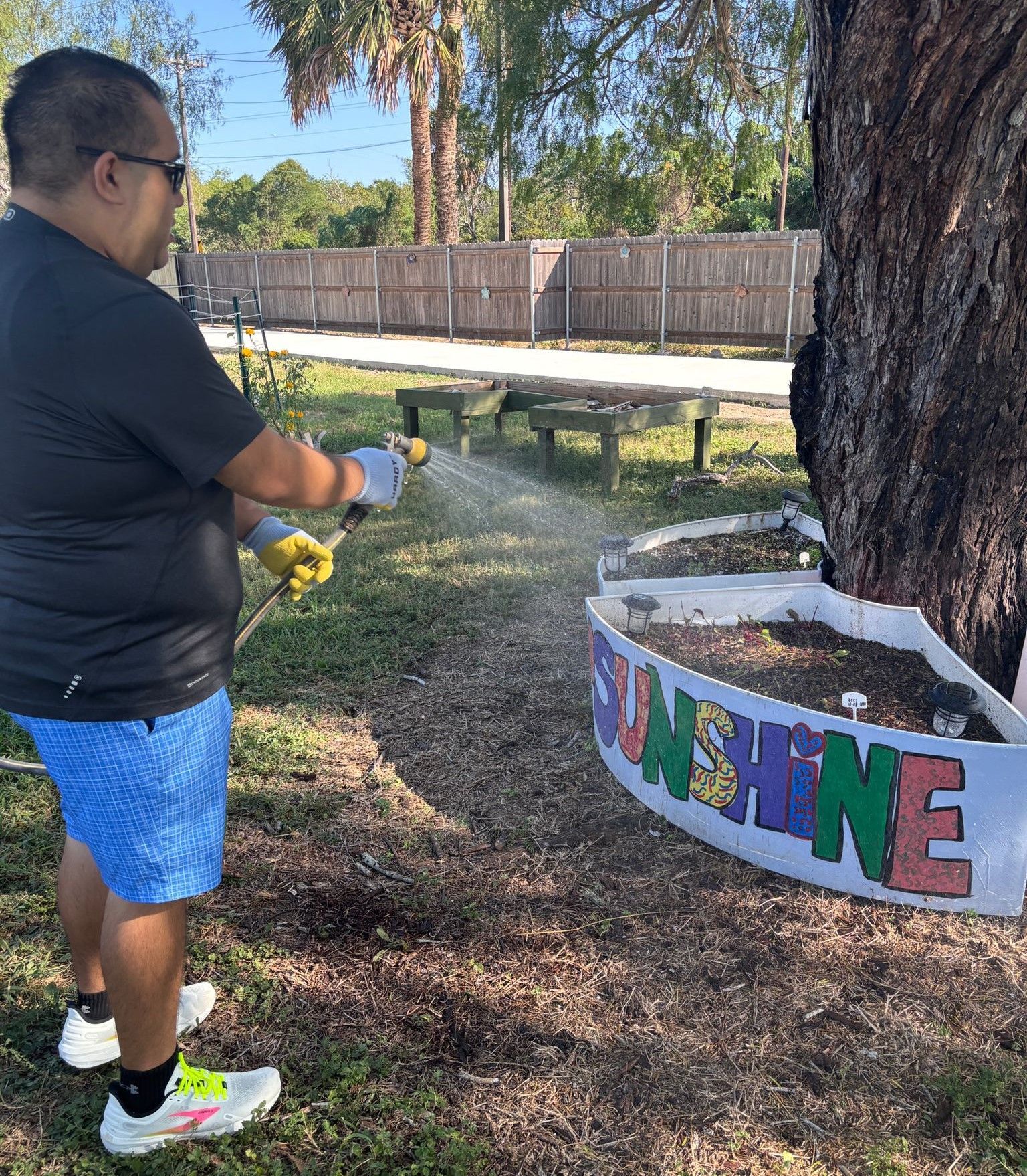 A man is spraying water on a sign that says sunshine