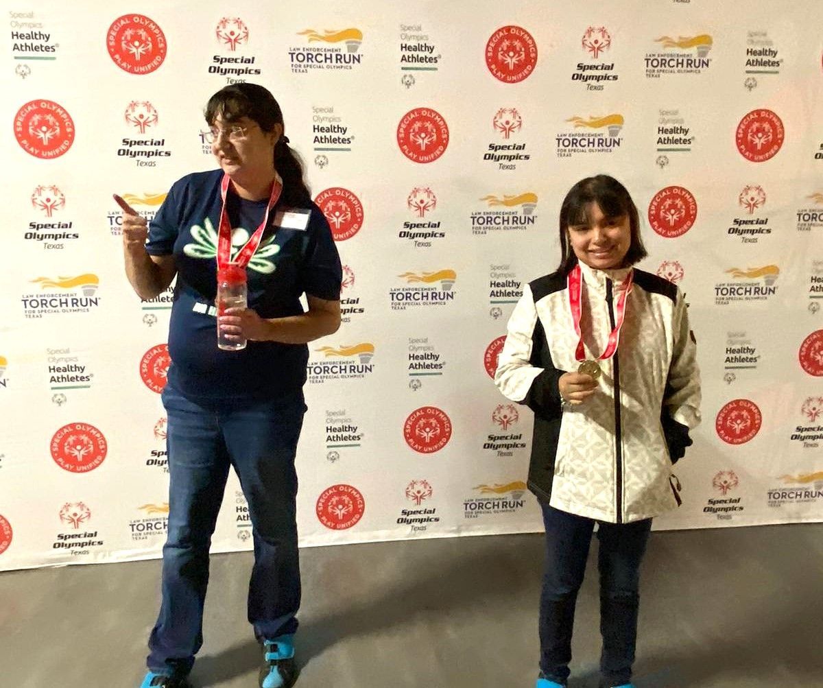 Two women are standing in front of a wall with circles on it.