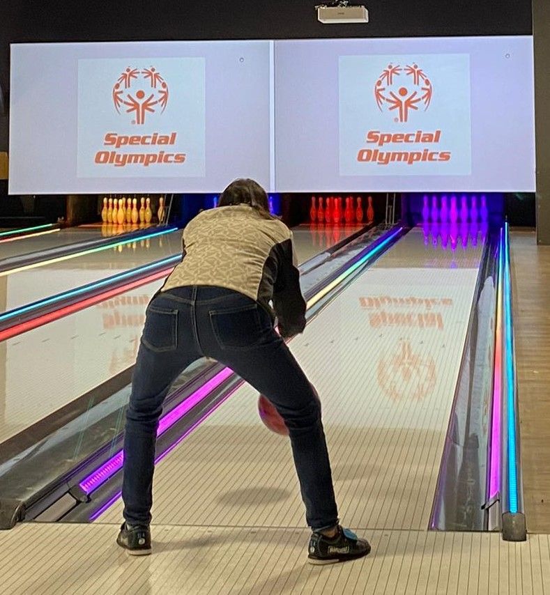 A woman is playing bowling in a special olympics bowling alley