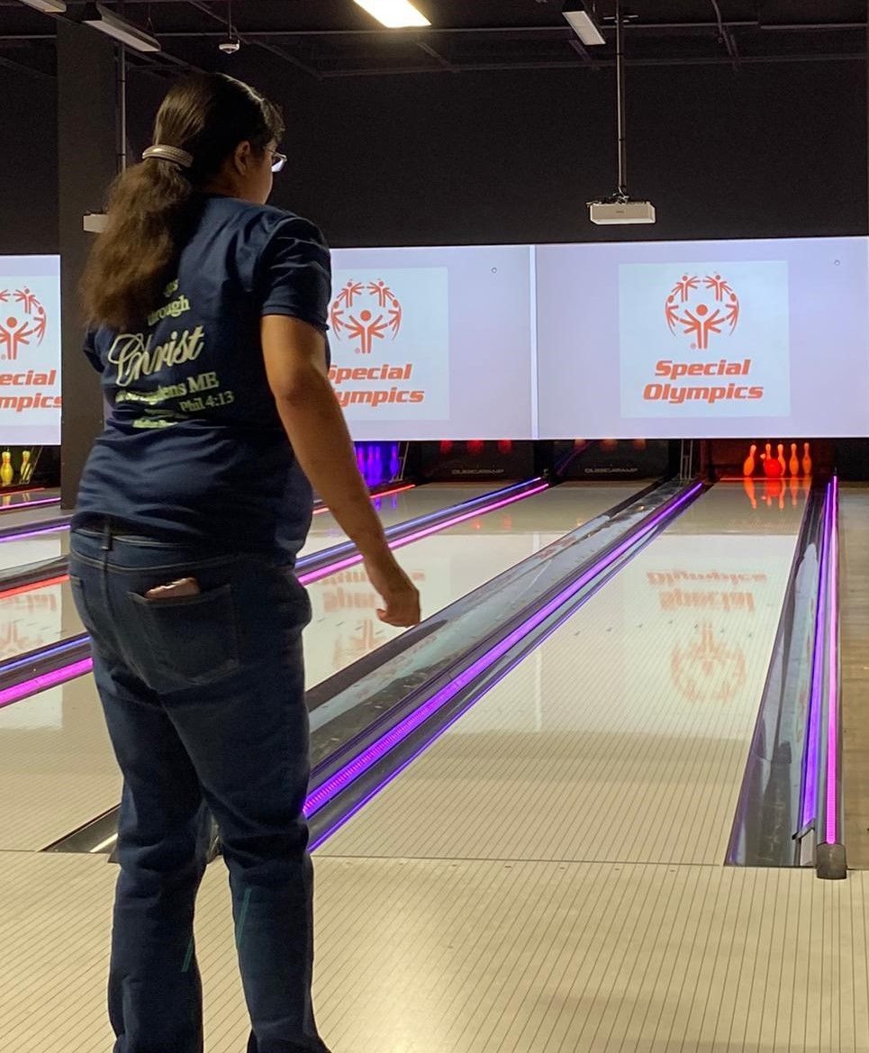 A woman in a blue shirt is playing bowling