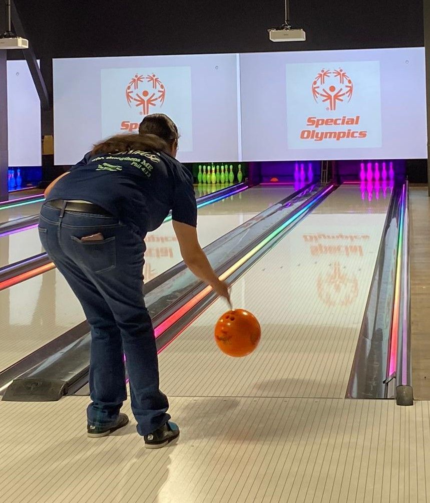 A woman is bowling at a special olympics bowling alley