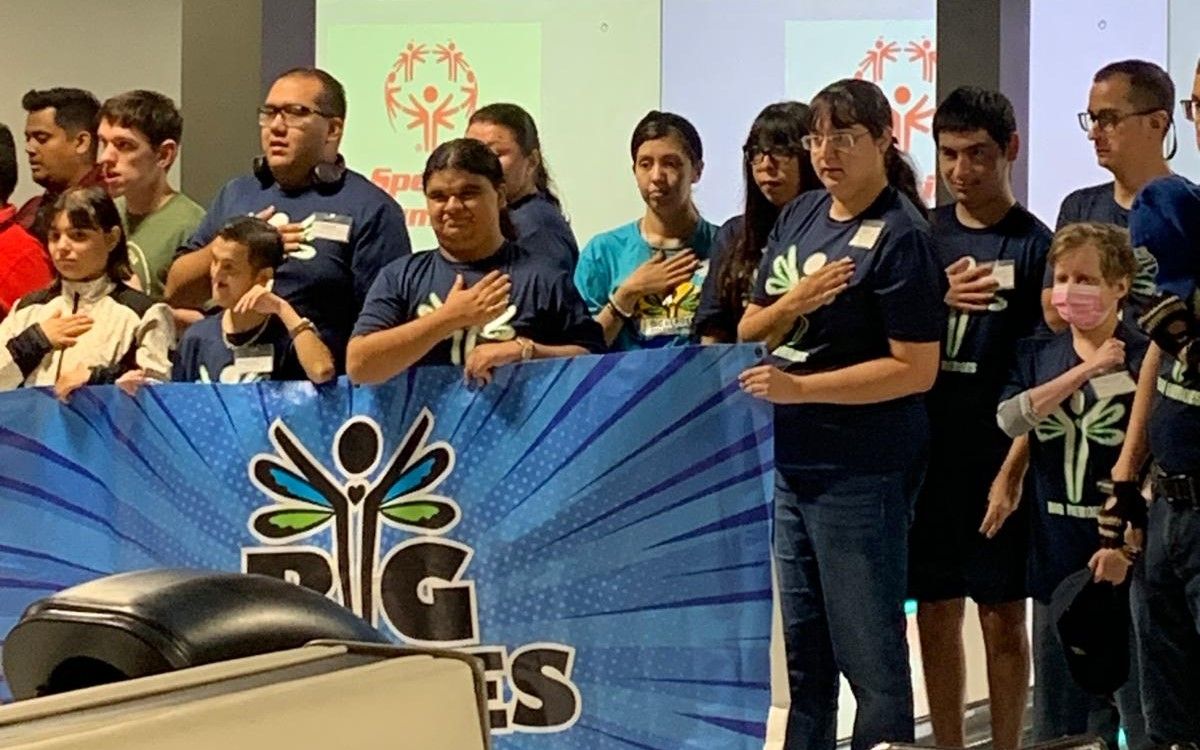 A group of people are standing in front of a sign that says big es.