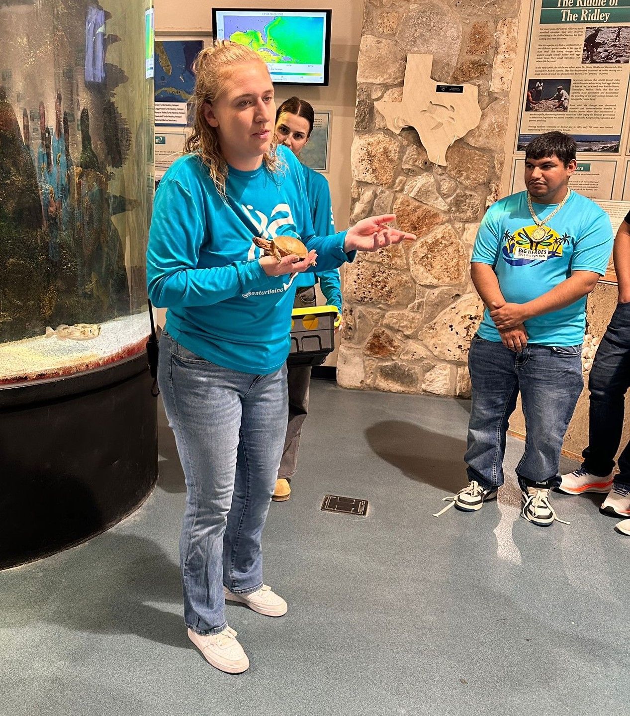 A woman in a blue shirt is talking to a group of people