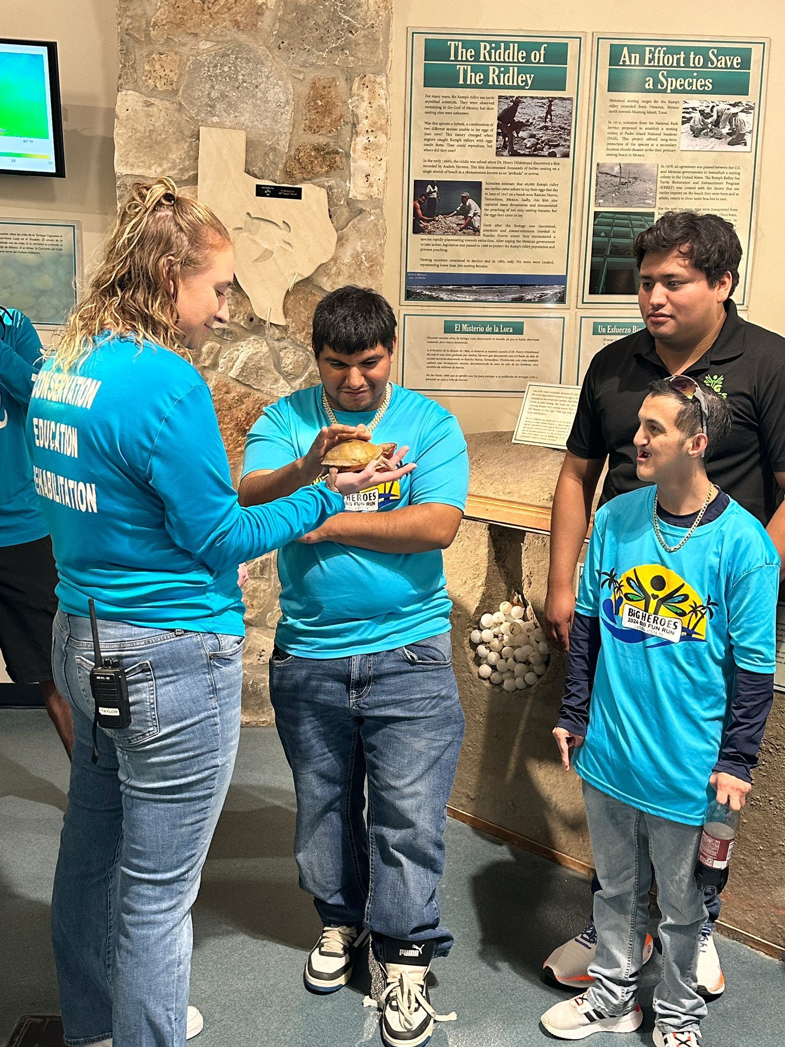 A group of people in blue shirts are standing next to each other in a room.