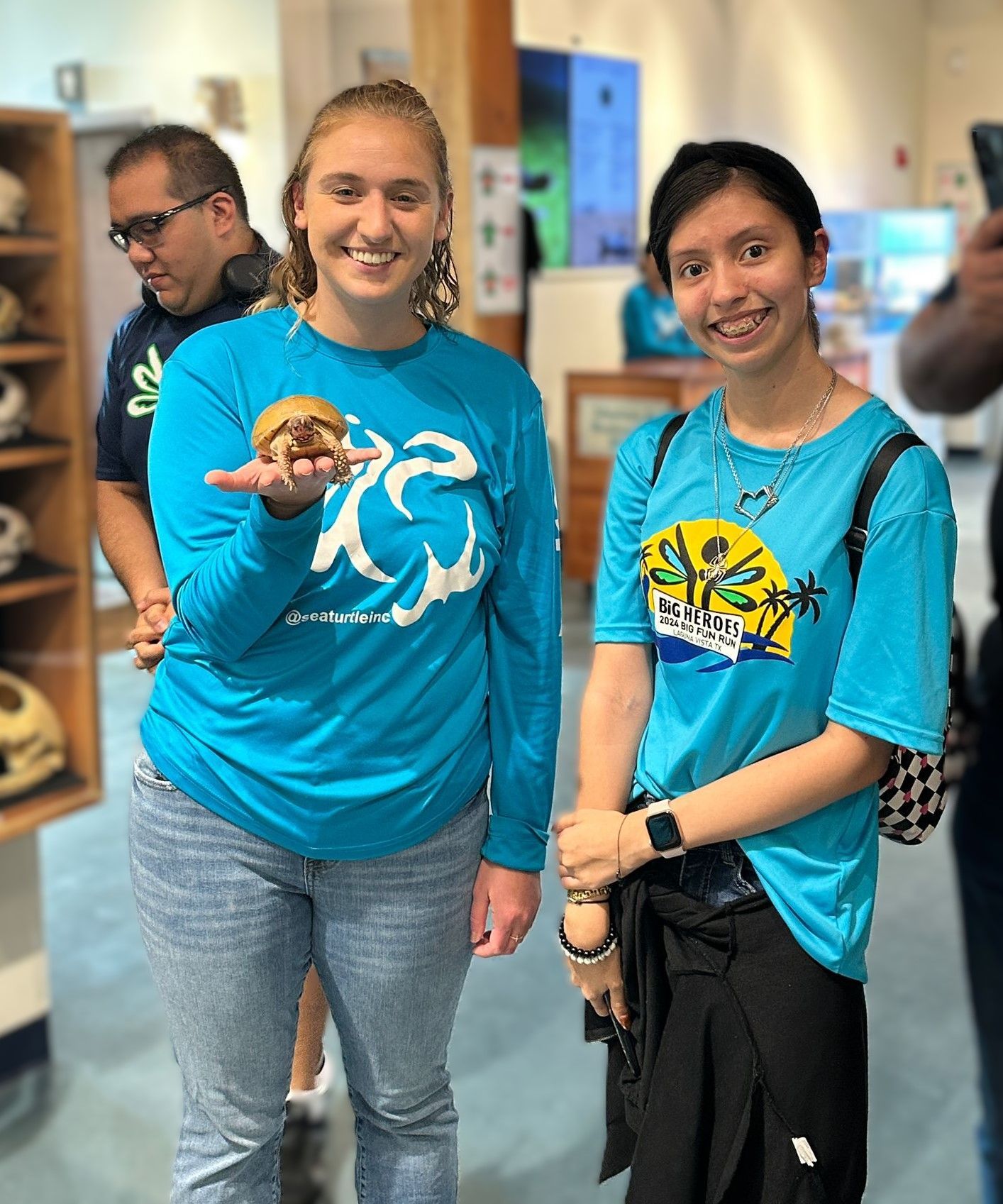 Two girls wearing blue shirts are standing next to each other in a room.