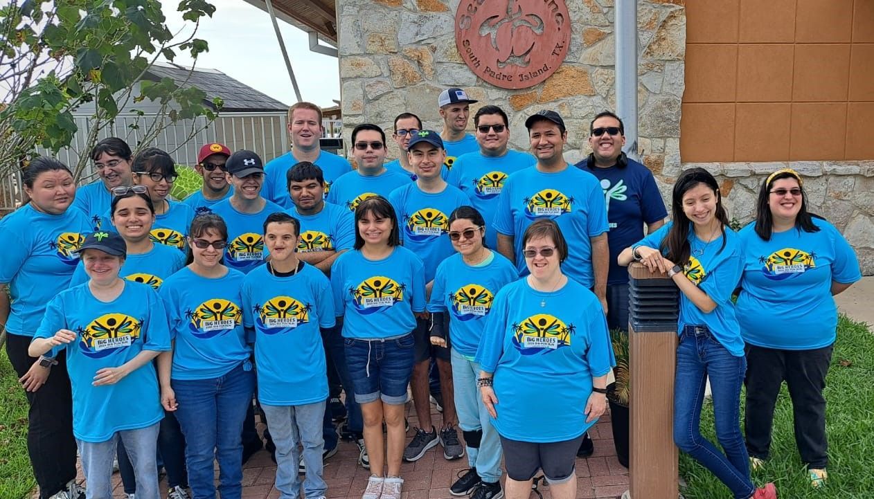A group of people wearing blue shirts are posing for a picture.