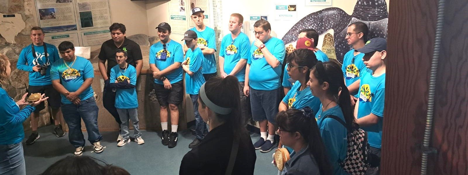 A group of people in blue shirts are standing in a room.