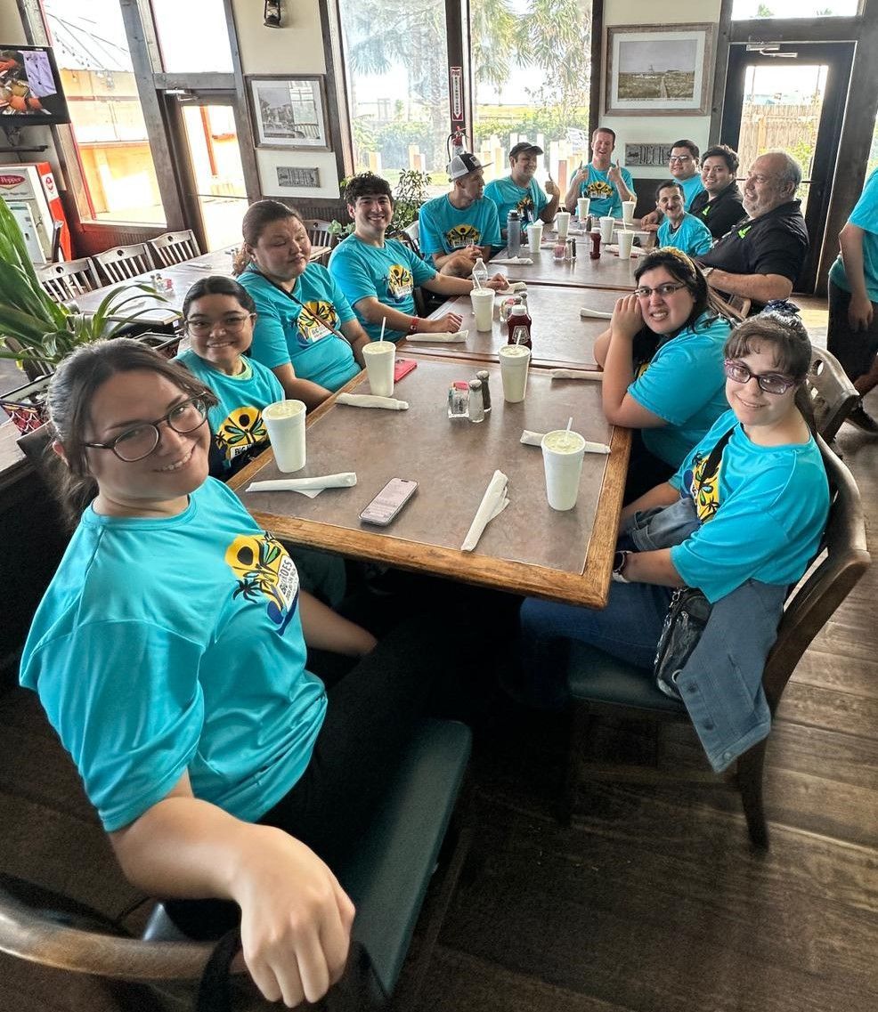 A group of people in blue shirts are sitting at a table in a restaurant.