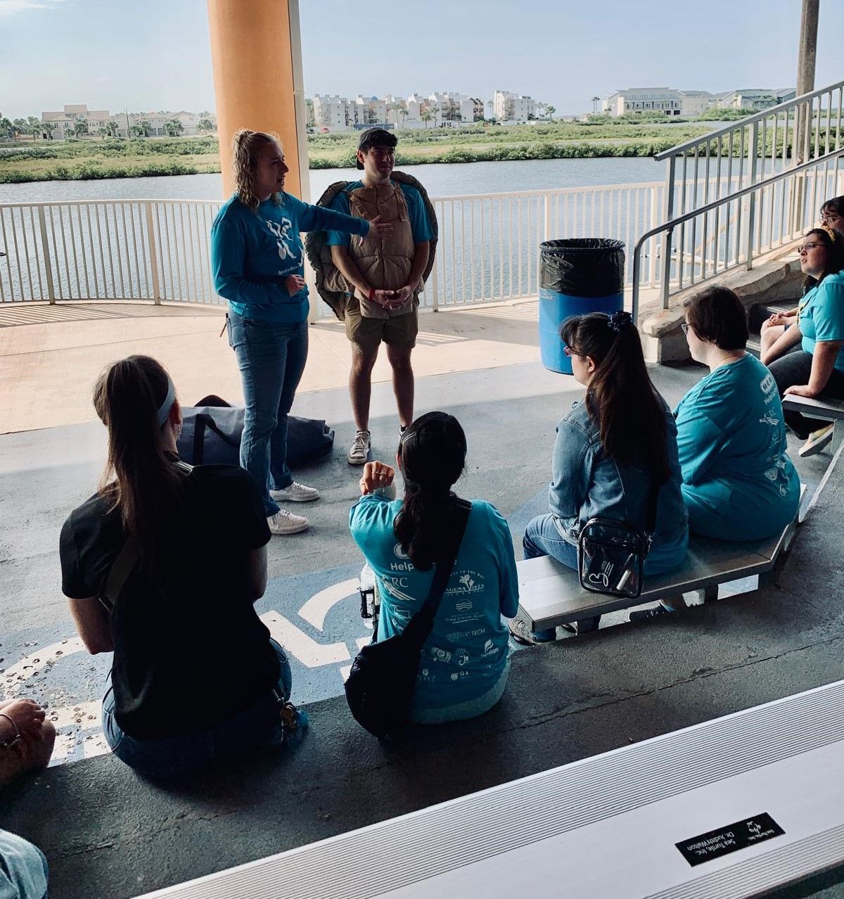 A group of people are sitting in a circle on a pier.