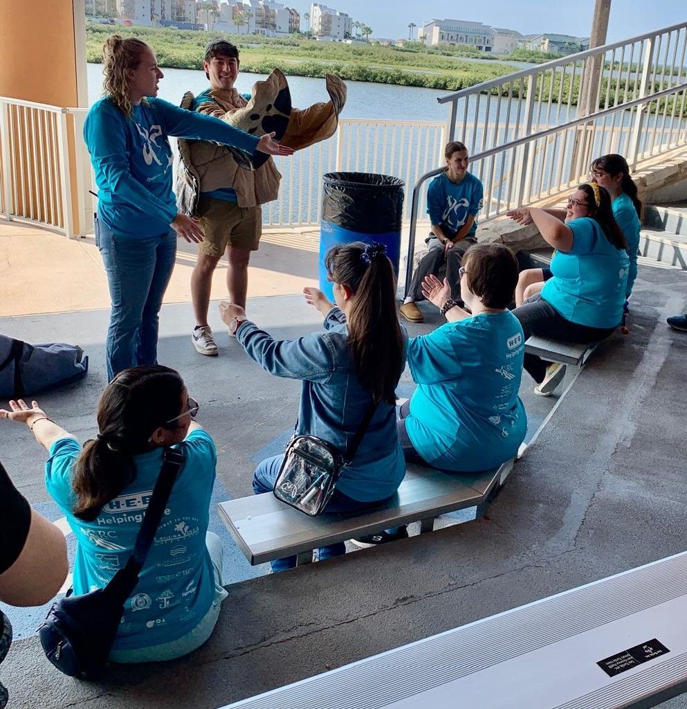 A group of people wearing blue shirts are sitting on benches.
