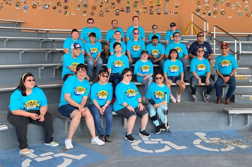 A group of people wearing blue shirts are sitting on bleachers.