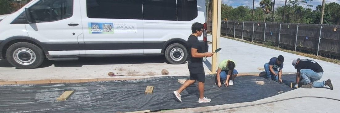 A group of people are working on a driveway in front of a white van.