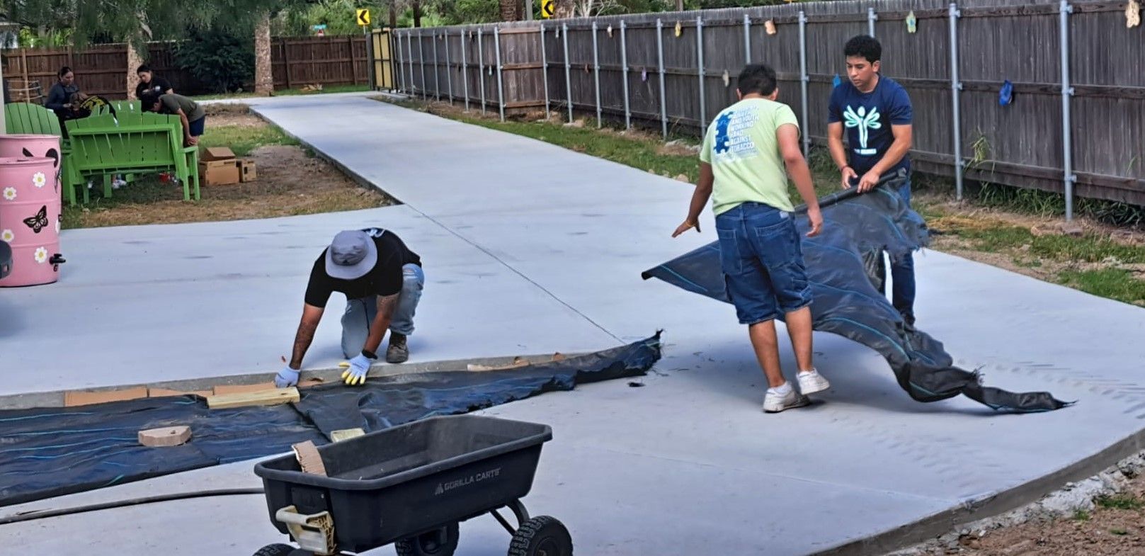 A group of men are working on a concrete driveway.