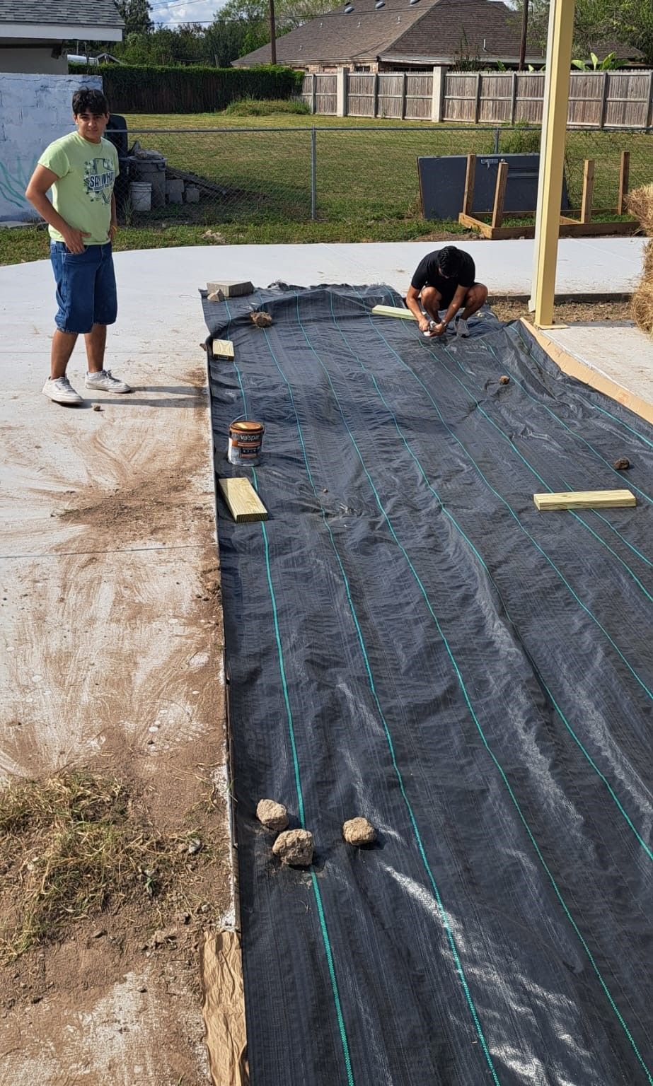 A man is standing next to a large piece of black tarp.