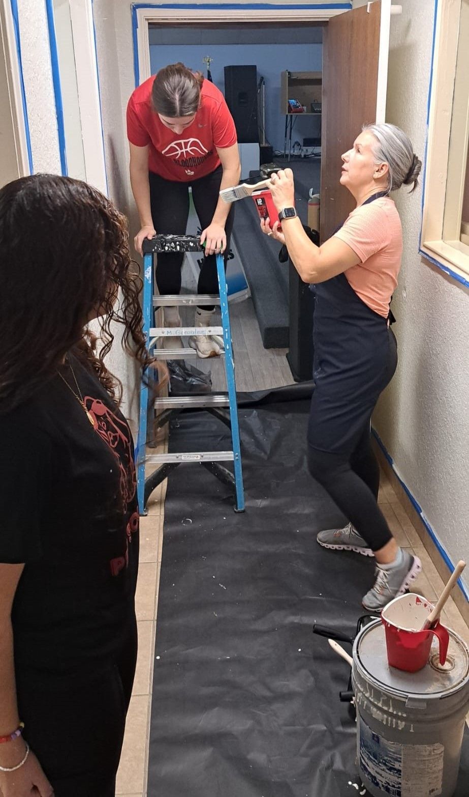 A man and a woman are painting a hallway.