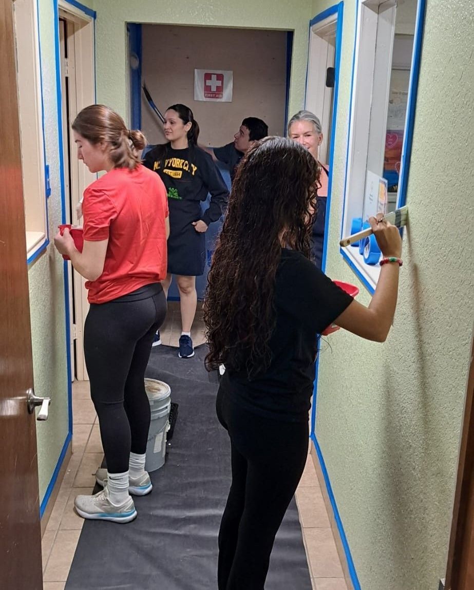 A woman is painting a wall in a hallway